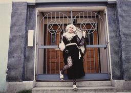 Sadie, Sadie the Rabbi Lady poses in front of a synagogue. Sadie, the drag persona of Gilbert Block, was a Jewish nun character and early member of the Sisters of Perpetual Indulgence, a group of drag nuns who do charitable work in San Francisco's queer community. The photograph was taken by Jean-Baptiste Carhaix, who photographed the Sisters extensively.