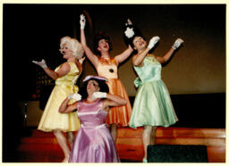 The Kinsey Sicks performing in pastel satin dresses, circa 1999-2007. From left to right: Trixie (Maurice Kelly), Rachel (Ben Schatz), Winnie (Irwin Keller), and Trampolina (Chris Dilley). 