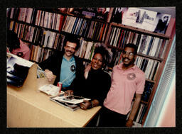 Photograph of Sylvester signing records in the record store, 12" Dance Records. Inscription on verso of photograph reads: "Sylvester, It was a pleasure to photograph you when you visited 12" Dance Records. Thank you for visiting us. Larry [Frazer?] the photographer. Dec. 1986."