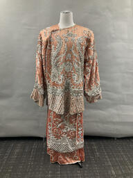 Peach sequined tunic and skirt with crane motif worn by Sylvester. This garment appears to be handmade and there is no designer label attached. This item is undated.