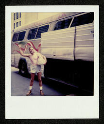 Photograph of a chorus member standing in front of the tour bus during their 1981 National Tour. This photograph is from a photo album belonging to Bill Graham, an early member of the Chorus. 