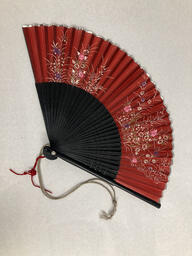 Red folding fan used by Finocchio's performers. This item is undated. 
