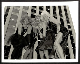 Photograph of the Kinsey Sicks posing in front of a skyscraper in San Francisco, CA. Members pictured include: Jerry Friedman (Vaselina), Ben Schatz (Rachel), Irwin Keller (Winnie), and Maurice Kelly (Trixie). 