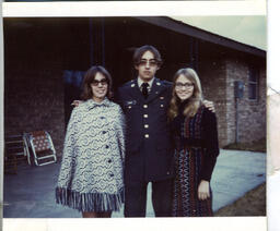 A Polaroid snapshot of a young Gilbert Baker in Army uniform, possibly with his mother and sister.