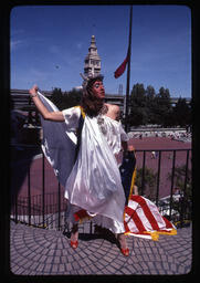 Gilbert Baker poses in drag in front of the San Francisco Ferry Building. Photograph by Jean-Baptiste Carhaix.